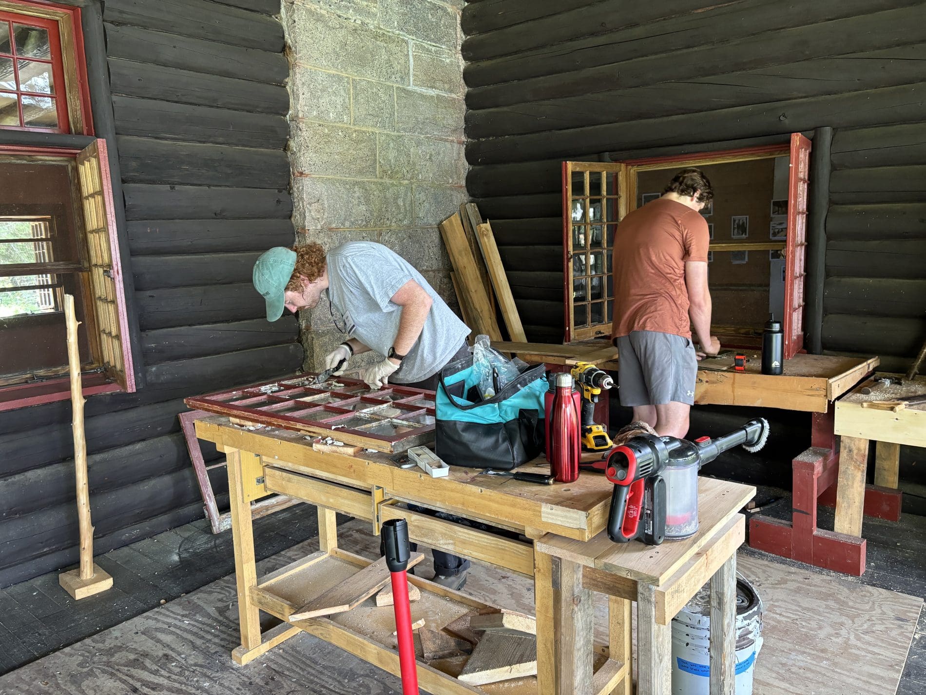 Two summer interns repairing windows on a historic porch