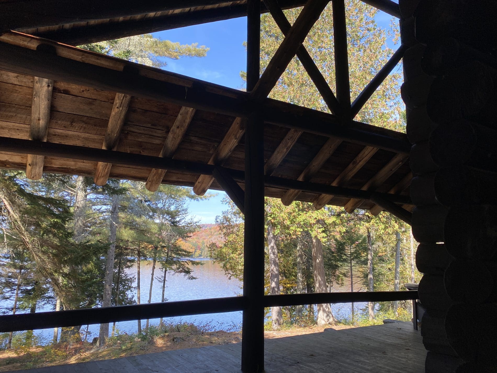 View of a wilderness lake from the porch of a rustic Adirondack great camp.